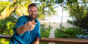 Na obrázku je muž, ktorý si užíva výhru v lotérii Eurojackpot v exotickej krajine.